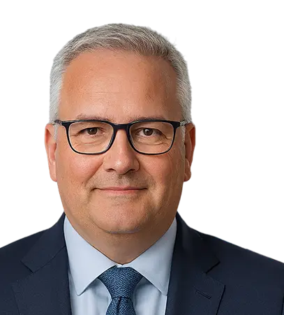 Professional portrait of a middle-aged businessman in glasses, wearing a dark suit, light blue shirt, and tie, smiling confidently.